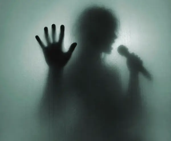 A shadowy hand pressed against misted glass